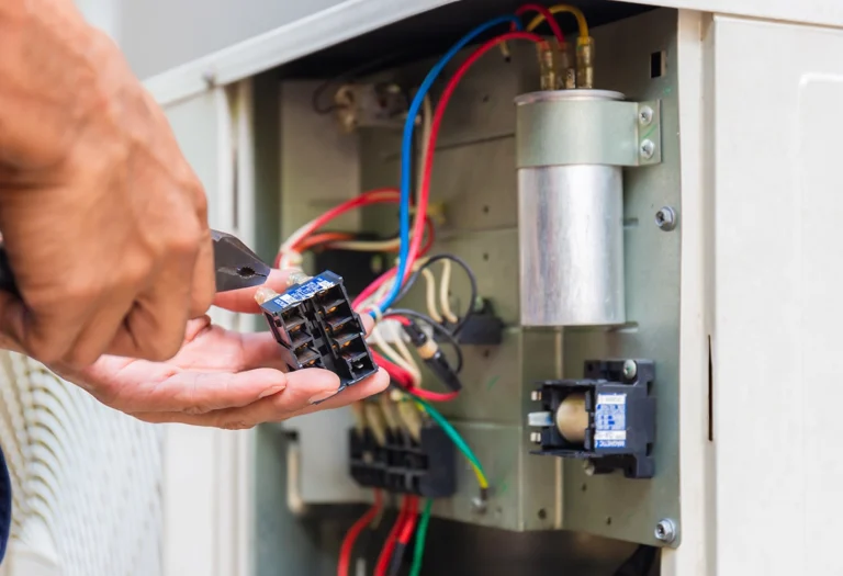 Close-up of an HVAC contactor being inspected or replaced inside an outdoor unit control compartment